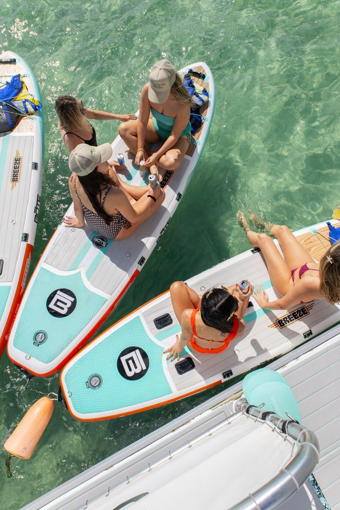 Guests sitting on paddleboards beside the boat, seen from above