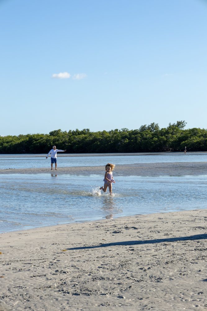 A child walking along the sandbar beach