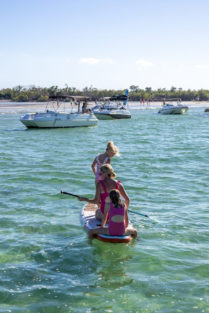 A girl paddleboarding near the boat in clear water