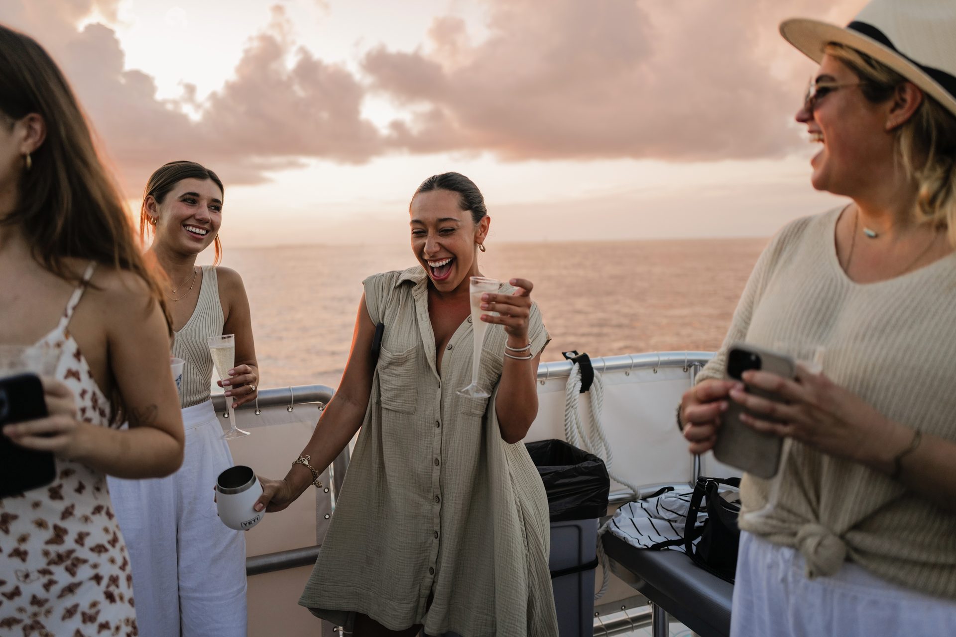 Guests laughing over drinks on the Brightwild boat in golden-hour light